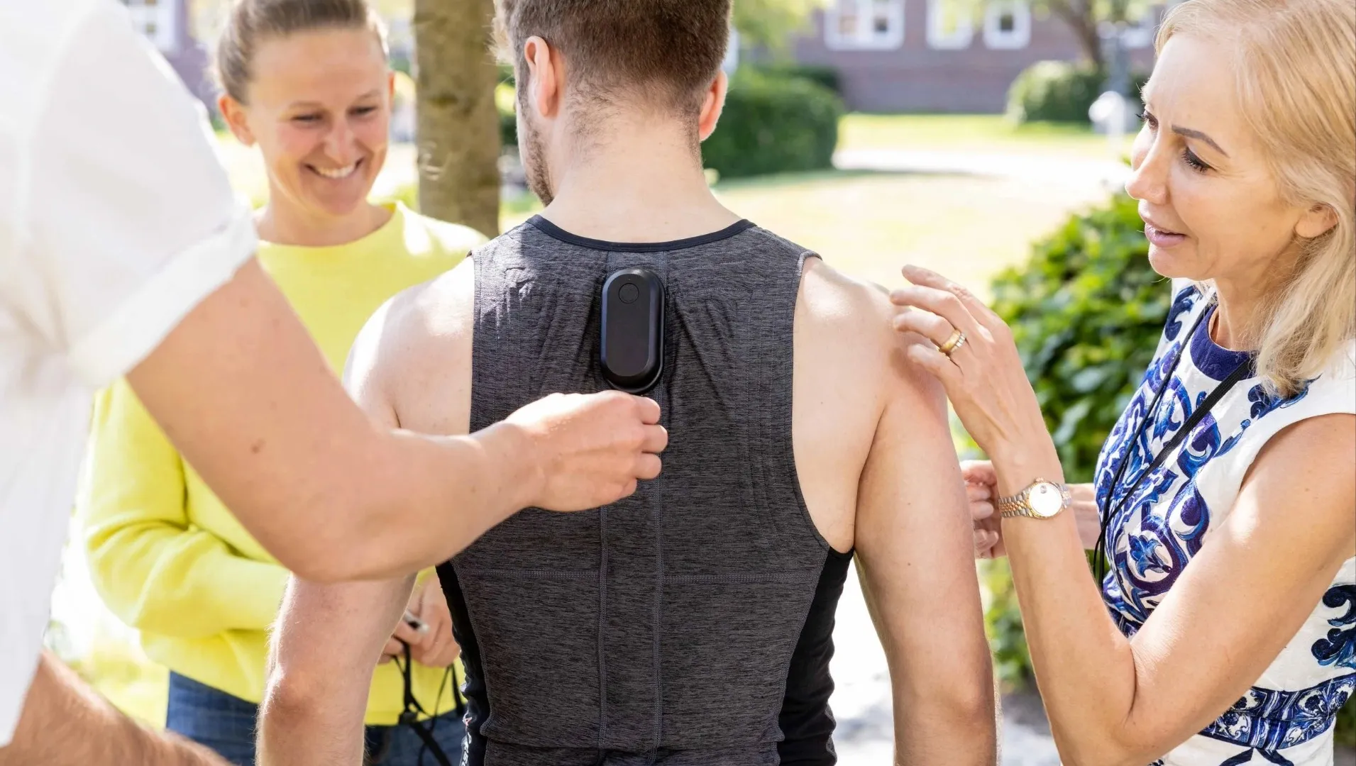 A colleague clips the Precure MLI® Back sensor to the back of a measurement vest while two others look on